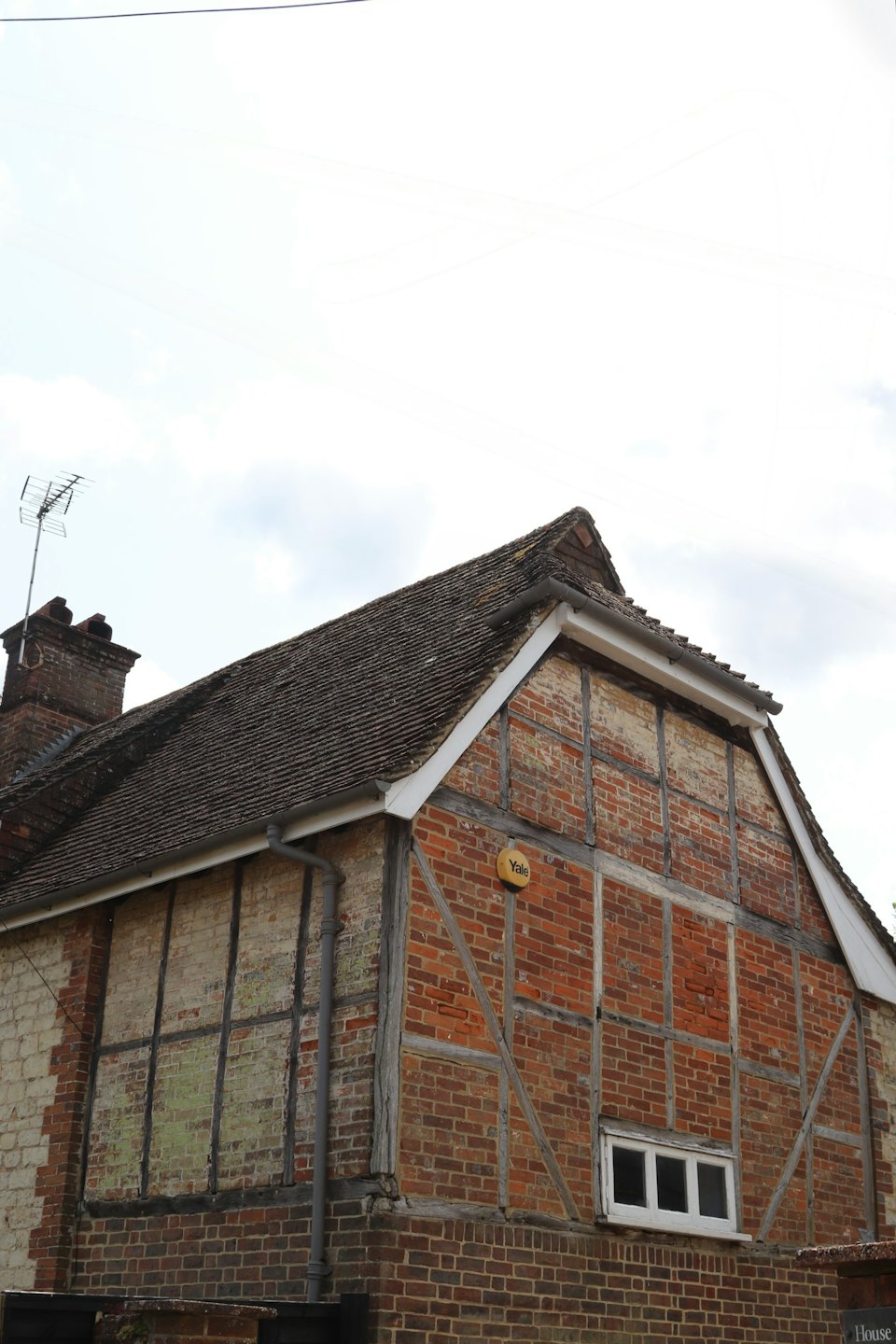Maison traditionnelle en briques et poutres avec un toit de tuiles moussues.