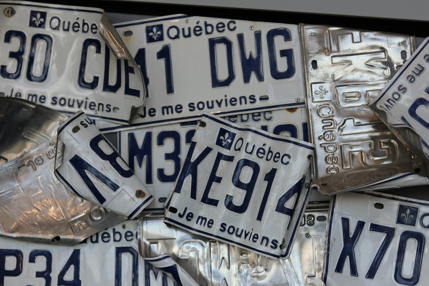 Une collection de plaques d'immatriculation du Québec qui se chevauchent avec des lettres bleues.