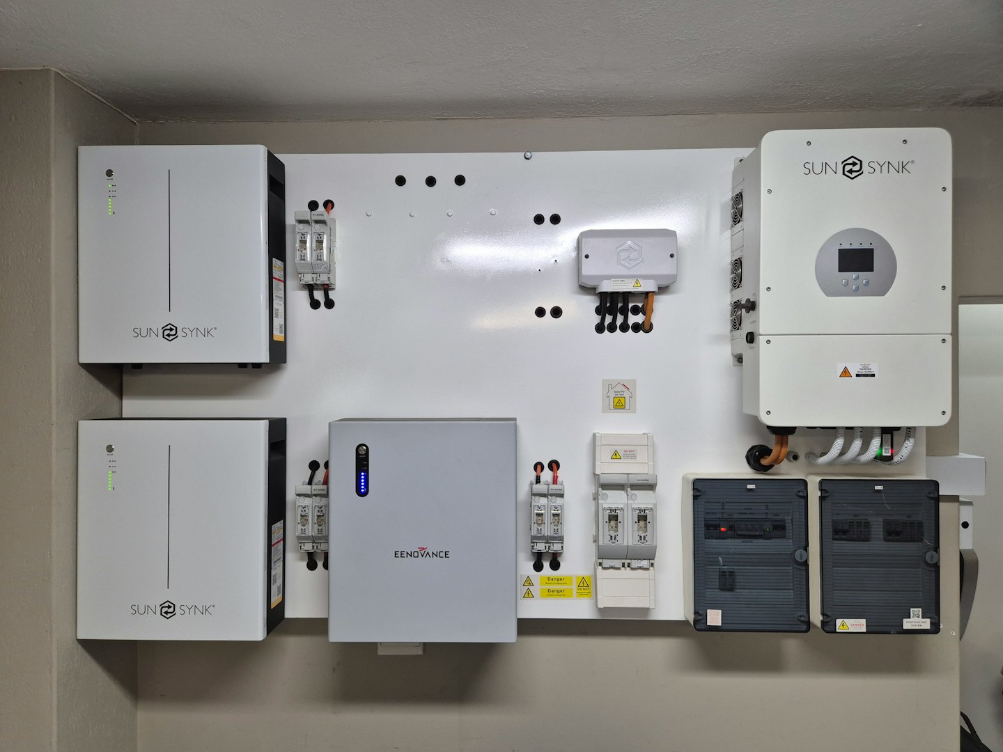 Système énergétique domestique avec batteries et onduleurs sur un mur blanc.